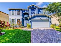 Beautiful two-story home with a well-maintained lawn, landscaped flowerbeds, and a brick driveway at 12715 Moss Park Ridge Dr, Orlando, FL 32832