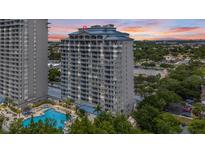 Striking building exterior featuring multiple balconies with sunset in the background and a glimpse of the community pool at 13415 Blue Heron Beach Dr # 401, Orlando, FL 32821