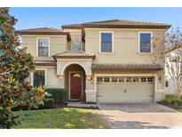 Elegant two-story home featuring a tile roof, arched entryway, and a well-maintained brick paver driveway at 1456 Belle Terre Rd, Davenport, FL 33896
