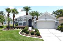 Charming home featuring mature palm trees, manicured landscaping, stone accents and a two-car garage at 1590 The Oaks Blvd, Kissimmee, FL 34746