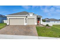 Charming single-story home with a three car garage, brick driveway, and manicured lawn at 168 Jensen Dr, Groveland, FL 34736