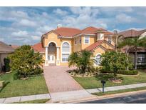 Stunning two-story home with a red tile roof, lush landscaping, and a brick driveway at 2333 Pinehurst Ct, Davenport, FL 33837