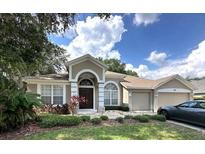 Charming single-story home with a well-manicured lawn, arched entryway, and attached two-car garage at 401 Chinahill Ct, Apopka, FL 32712