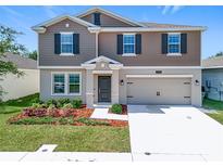 Charming two-story home featuring a well-manicured lawn, a two-car garage and complementary landscaping at 5712 Bristleleaf Ct, Leesburg, FL 34748