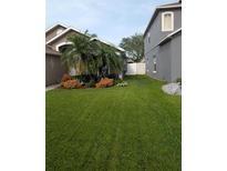 Landscaped front yard with lush lawn, a palm tree, and colorful flower beds surrounding the home at 5921 Lake Champlain Dr, Orlando, FL 32829