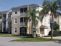 Inviting multi-story condo building featuring screened balconies and lush landscaping on a sunny day at 8101 Coconut Palm Way # 303, Kissimmee, FL 34747