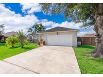 Exterior view of a home featuring a two-car garage and a long concrete driveway at 812 Adour Dr, Kissimmee, FL 34759