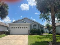 Charming single-Gathering home featuring an attached two-car garage and tropical landscaping at 123 S Roma Way, Kissimmee, FL 34746