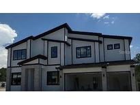 Modern two-story home with a light colored exterior, gray stone accents, black trim, and a two car garage at 1431 Butterfly, Davenport, FL 33837
