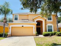 Inviting two-story home with a two-car garage, mature landscaping, and a well-maintained lawn at 2514 Dharma Cir, Kissimmee, FL 34746