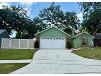 Charming single-Gathering home features a lush front lawn, mature trees, and a two-car garage at 2779 Theresa Dr, Kissimmee, FL 34744