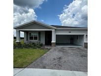 Inviting single-Gathering home features a brick-paved driveway, two-car garage, and charming front porch at 4053 Redbridge Loop, Davenport, FL 33837