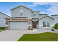 Charming two-story home with a stone-accented facade, well-maintained lawn and inviting red front door at 454 Hamlet Loop, Davenport, FL 33837
