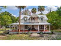 Charming two-story home featuring a large front porch with beautiful architectural details and mature trees at 525 W Blue Springs Ave, Orange City, FL 32763