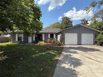Charming single-story home with a two-car garage, gray siding, stone accents, and a well-maintained lawn at 6489 Creation St, St Cloud, FL 34771