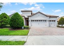 Charming single-story home with a tile roof, three-car garage and manicured landscaping at 1394 Palmetto Dunes St, Champions Gate, FL 33896