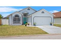 Charming single-Gathering home features a teal front door, well-maintained lawn, and an attached two-car garage at 142 Ethan Ave, Davenport, FL 33897