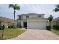 Charming two-story home with a brick driveway, well-manicured lawn and a palm tree at 257 Lancaster Dr, Davenport, FL 33897
