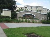 Stone sign for Verona Ridge community with manicured landscaping and multi-story buildings in the background at 3001 Greystone Loop # 106, Kissimmee, FL 34741