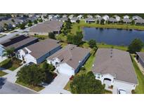 An aerial view of a neighborhood showcases the house, its well-maintained lawn, and a nearby pond, all under a bright, sunny sky at 3333 Sagebrush St, Harmony, FL 34773