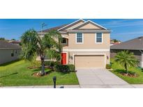 Two-story home featuring a two-car garage, well-kept lawn, mature landscaping, and a vibrant red front door at 3391 Cortland Dr, Davenport, FL 33837