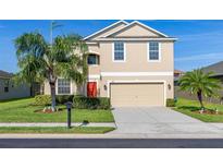 Two-story home with a two car garage, landscaped yard and a vibrant red front door at 3391 Cortland Dr, Davenport, FL 33837