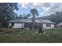 The backyard includes a screened in porch, dead tree branches, and sparse, patchy grass at 4345 Old Colony Rd, Mulberry, FL 33860
