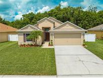Charming single-story home featuring a well-manicured lawn, mature landscaping, and an attached two-car garage at 4726 Ashurst St, Kissimmee, FL 34758