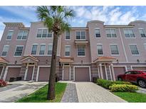 Three-story townhome featuring individual garages, private entrances and lush tropical landscaping with palm tree at 5038 Tideview Cir # 21, Orlando, FL 32819