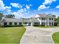 Stately two-story home features white columns, lush landscaping, and a long driveway at 5150 Gentry Oaks Pl, St Cloud, FL 34772