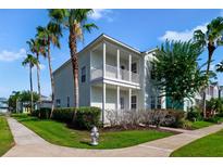 Charming two-story home with a double balcony, palm trees, and beautiful landscaping at 7740 Linkside Loop, Reunion, FL 34747
