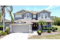 Charming two-story home with gray stucco, neutral trim, attached two-car garage, and well manicured landscaping at 805 Suffolk Pl, Davenport, FL 33896