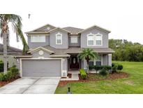 Charming two-story home featuring a manicured lawn, mature landscaping, and a two car garage at 805 Suffolk Pl, Davenport, FL 33896