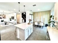 Open-concept kitchen features a white island, granite countertops, and pendant lighting adjacent to a dining area at 921 Spring Palms Loop, Orlando, FL 32828
