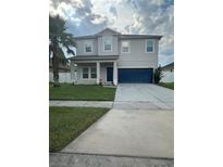 Two-story home featuring a well-maintained lawn, a two-car garage, and a charming covered front porch at 12372 Stone Bark Trl, Orlando, FL 32824