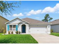Charming single-story home featuring a two-car garage, well-kept lawn, and blue shutters at 2416 White Poppy Dr, Kissimmee, FL 34747