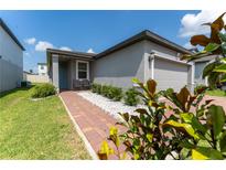 Charming single-story home featuring a gray exterior, a brick walkway, and manicured landscaping at 3442 Monaco Ln, Davenport, FL 33897