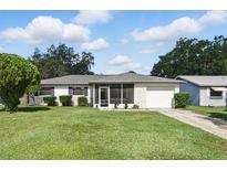 Charming one-story home with a well-maintained lawn, attached garage, and a screened-in porch, exuding curb appeal at 412 Georgia Ave, St Cloud, FL 34769