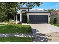Charming single-Gathering home featuring a gray roof, a two-car garage, and well-maintained landscaping at 4903 Santa Clara Dr, Orlando, FL 32837