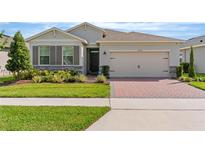 Charming single-story home with a well-manicured lawn, brick driveway, and neutral stucco exterior at 17795 Blazing Star Cir, Clermont, FL 34714