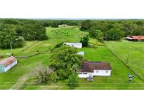 An aerial view of a property with mature trees and a quaint house nestled in a lush green landscape at 1886 Pleasant Hill Rd, Kissimmee, FL 34746