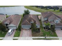An aerial view of a home with a brick driveway and tile roof near a lake in a residential neighborhood at 2016 Lakeside Ave, Davenport, FL 33837