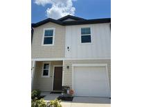 Charming two-story home with a white garage door, a dark brown entry door, and a manicured lawn at 254 Mandovi St, Davenport, FL 33837
