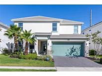 Inviting two-story home with a well-manicured lawn, palm trees, and a driveway with a two-car garage at 2623 Calistoga Ave, Kissimmee, FL 34741