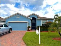 Charming single-story home with blue exterior, brick driveway, and well-manicured lawn at 2919 Woodward Ln, Winter Haven, FL 33884