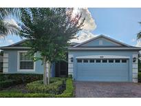 Charming single-story blue home with a brick driveway, attached garage, and manicured landscaping at 3606 Solana Cir, Clermont, FL 34711
