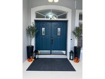 Stylish blue double front door with sidelights, decorative plants, and lanterns create a welcoming entrance at 426 Cardinal Ct, Kissimmee, FL 34759