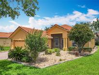 Charming single-story home featuring a terracotta tile roof, complemented by a well-manicured lawn and landscape at 572 Sienna Dr, Poinciana, FL 34759