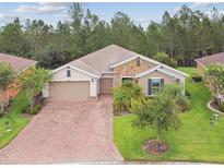 Charming single-story home featuring a brick driveway, manicured lawn, stone accents, and a two-car garage at 726 Irvine Ranch Rd, Kissimmee, FL 34759