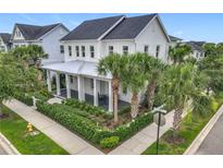 Charming two-story home with a metal roof, inviting front porch, well-manicured landscaping, and palm tree accents at 960 Civitas Way, Winter Garden, FL 34787